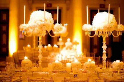 Kompozíció egy esküvői asztal, csillárokkal és oszlopok dekoráció kiszolgálása esküvői asztalra -