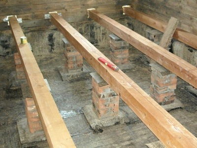 Dispozitivul unei podele din lemn pe bușteni, instalarea și stivuirea lor, un pas de distanță, coloane