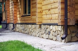 Finisarea fundatiei unei case de lemn din exterior cu tencuiala si alte materiale