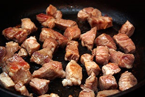 Carne de porc prăjită cu dovlecei într-o tigaie