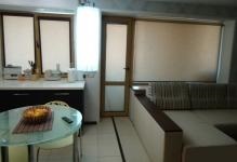 Bucătărie în bucătărie în camera de bucătărie-cameră de zi cu o canapea, combinată cu o masă rotundă, design semicircular
